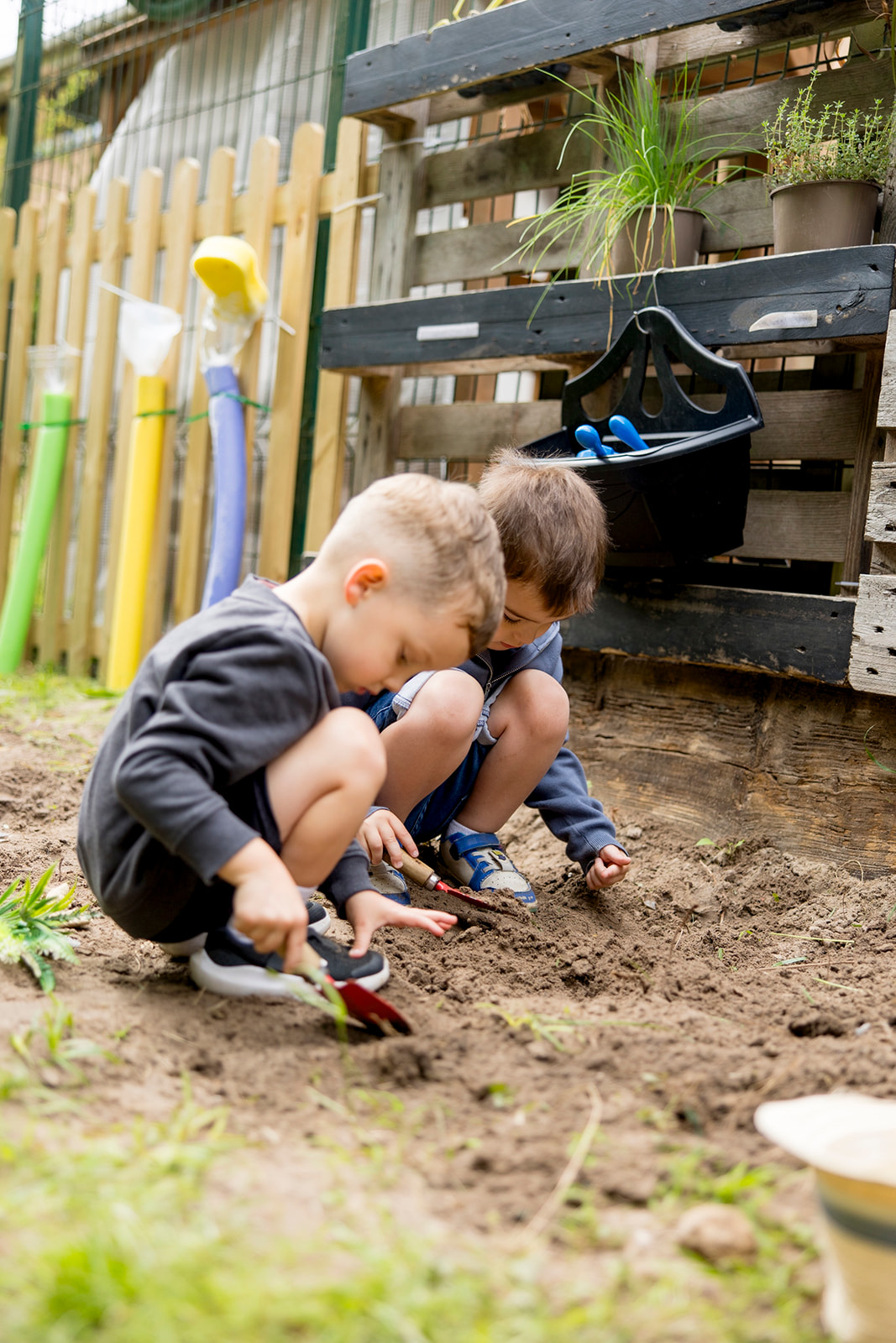 Two boys digging with trowels beside the planting beds in the garden