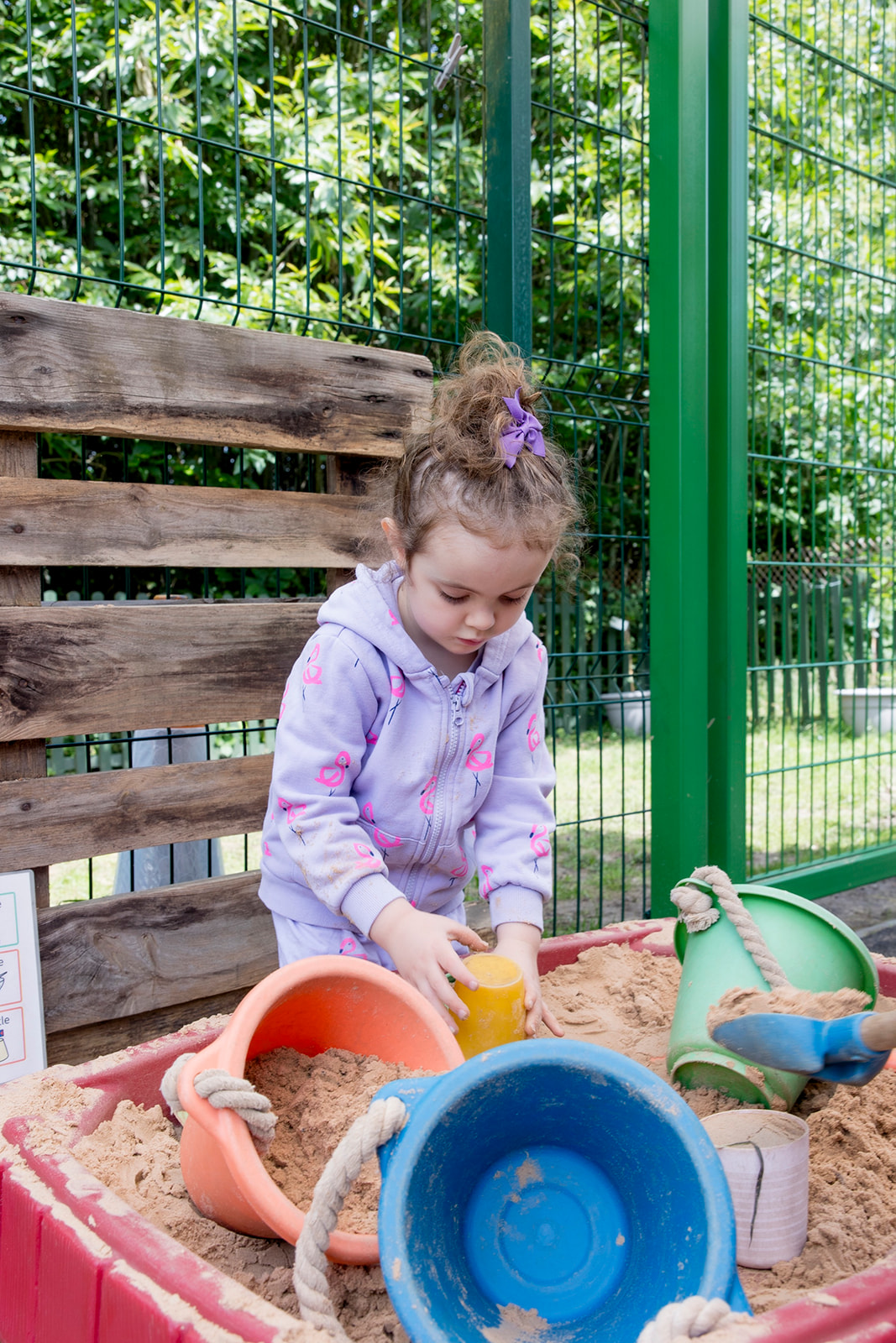 A girl filling buckets with sand in the preschool sandpit