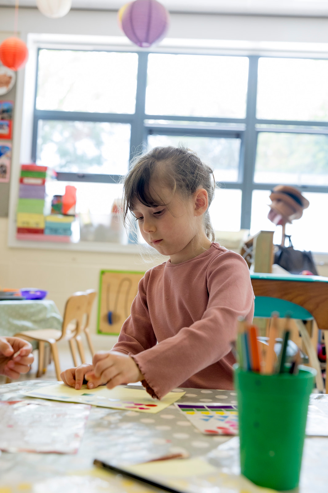 A girl placing coloured stickers onto paper at the making table